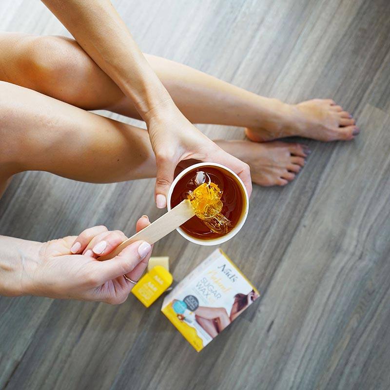 Woman applying Nad's Natural Sugar Wax hair removal wax to legs